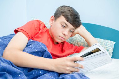Beyaz genç çocuk yatağı üzerinde döşeme bir kitap okuma