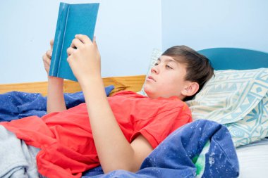 Beyaz genç çocuk yatağı üzerinde döşeme bir kitap okuma