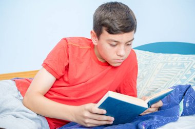 Beyaz genç çocuk yatağı üzerinde döşeme bir kitap okuma