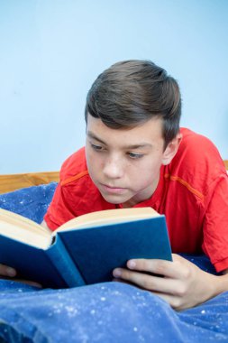 Beyaz genç çocuk yatağı üzerinde döşeme bir kitap okuma