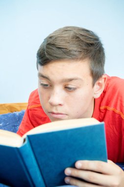 Beyaz genç çocuk yatağı üzerinde döşeme bir kitap okuma