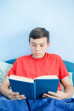 Beyaz genç çocuk yatağı üzerinde döşeme bir kitap okuma
