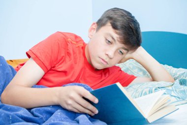 Beyaz genç çocuk yatağı üzerinde döşeme bir kitap okuma