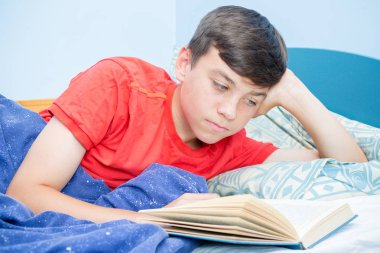 Beyaz genç çocuk yatağı üzerinde döşeme bir kitap okuma