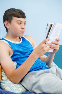 Beyaz genç çocuk yatağı üzerinde döşeme bir kitap okuma