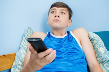 Bir uzaktan kumanda ile tv kanallar aracılığıyla flicking beyaz genç çocuk