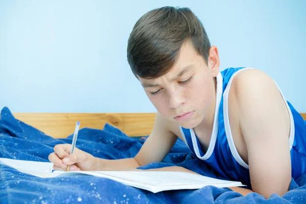 教科書を読んで彼のベッドを置くこと白人の 代の少年 — ストック写真