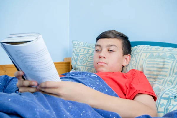 ベッドの上に敷設読書白人の 代の少年 — ストック写真