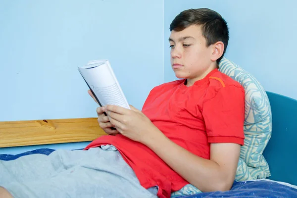 ベッドに座り本を読んで 代の白人の少年 — ストック写真