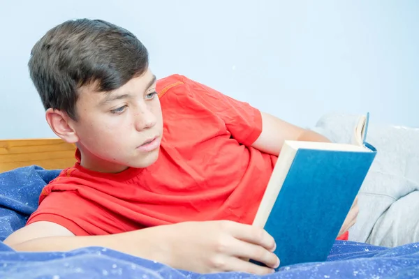 Beyaz genç çocuk yatağı üzerinde döşeme bir kitap okuma