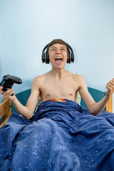 Genç çocuk yatak ve kazanan oturma sırasında bilgisayar oyunu oynamak