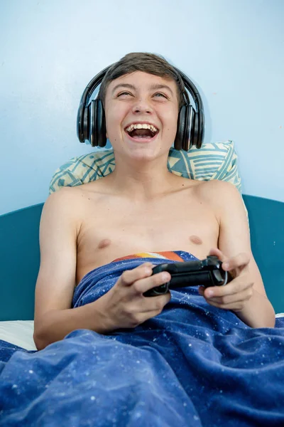 Genç çocuk yatak ve kazanan oturma sırasında bilgisayar oyunu oynamak