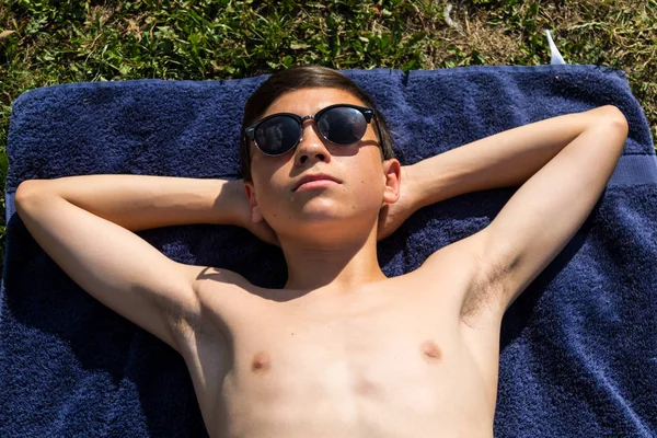 Beyaz genç çocuk güneş gözlüğü takıyor bir bahçede güneşlenme