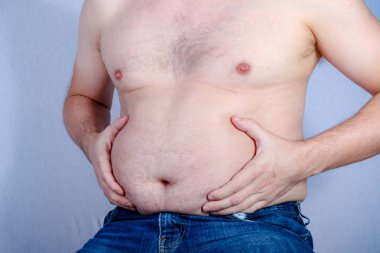 Kilolu gömleksiz beyaz adam onun karın yağ holding