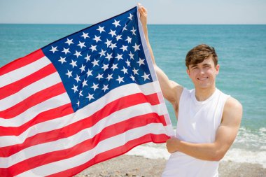 Sahilde amerikan bayrağı tutan beyaz erkek
