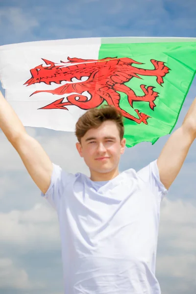 Blanc mâle sur une plage tenant un drapeau gallois — Photo
