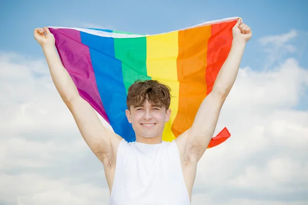 Caucasian male on a beach holding a Pride flag — Stock Photo, Image