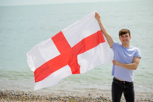 Kaukasiska hane på en strand som innehar en engelsk flagga — Stockfoto