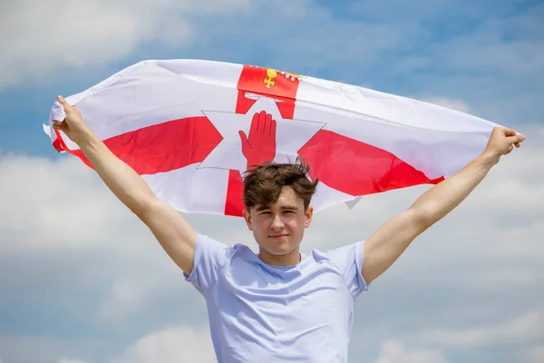 Blanc mâle sur une plage tenant un drapeau Ulster — Photo