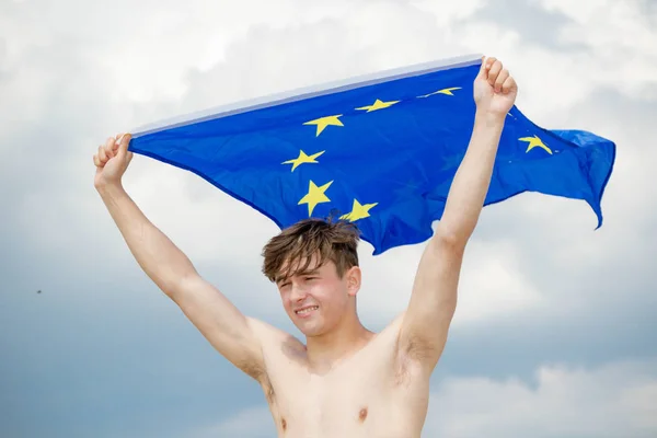 Kaukasiska hane på en strand som innehar en EU-flagga — Stockfoto