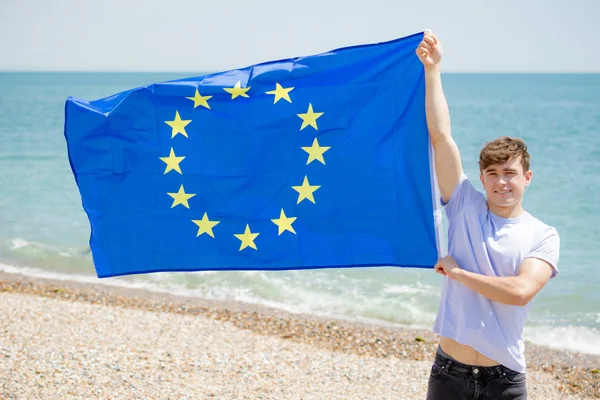 Beyaz erkek bir Avrupa Birliği bayrağı tutan bir plajda — Stok fotoğraf