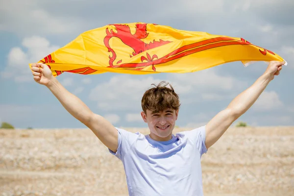 Blanc mâle sur une plage tenant un lion rampant de l'Ecosse fla — Photo