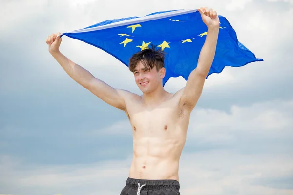 Maschio caucasico su una spiaggia con bandiera UE — Foto Stock