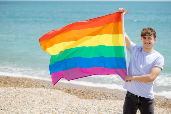 Maschio caucasico su una spiaggia con una bandiera Pride — Foto Stock