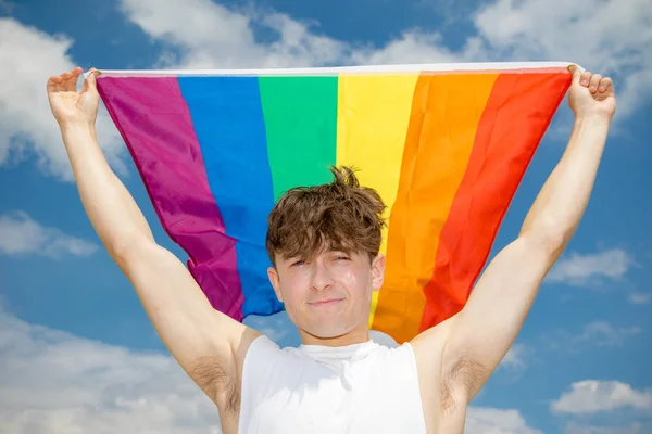 Caucasian male on a beach holding a Pride flag — Stock Photo, Image