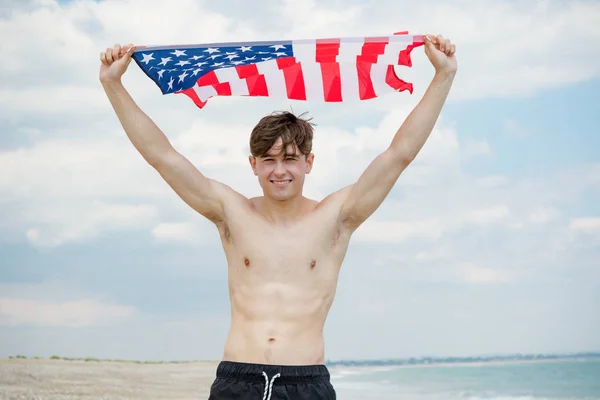 Kaukasischer Mann an einem Strand mit amerikanischer Flagge — Stockfoto