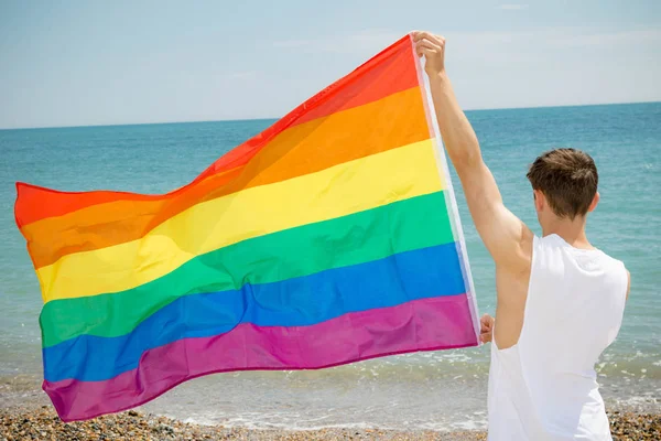 Hombre caucásico en una playa con bandera de Orgullo — Foto de Stock