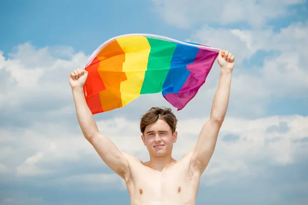 Caucasian male on a beach holding a Pride flag — Stock Photo, Image