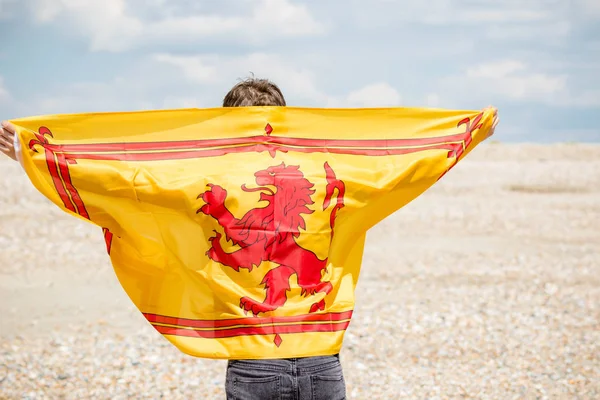 Blanc mâle sur une plage tenant un lion rampant de l'Ecosse fla — Photo