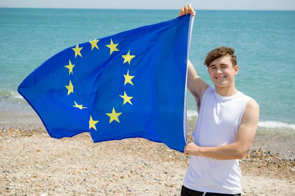 Homme caucasien sur une plage tenant un drapeau de l'UE — Photo