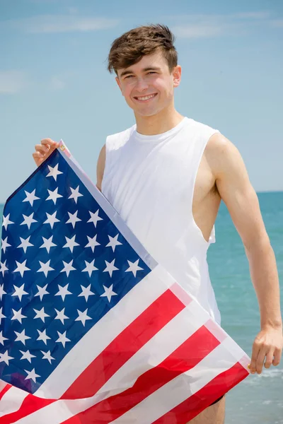 Blanc mâle sur une plage tenant un drapeau américain — Photo