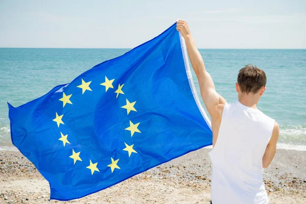 Καυκάσιος άντρας σε παραλία που κατέχει σημαία της ΕΕ — Φωτογραφία Αρχείου