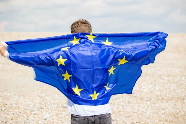 Kaukasiska hane på en strand som innehar en EU-flagga — Stockfoto