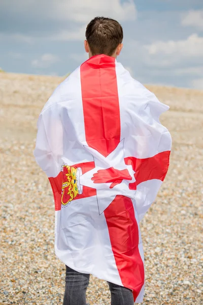 Blanc mâle sur une plage tenant un drapeau Ulster — Photo