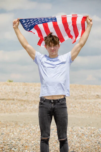 Hombre caucásico en una playa con bandera americana — Foto de Stock