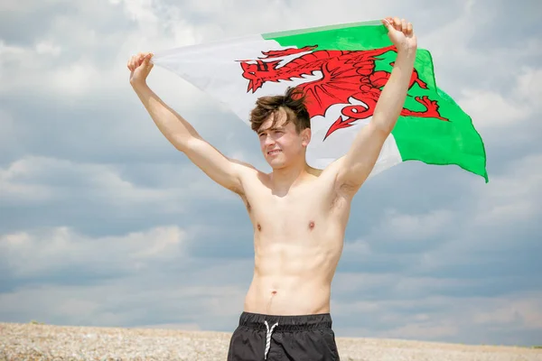 在沙滩上拿着威尔士国旗的白种人男性 — 图库照片
