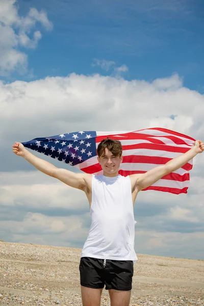 Kavkazský samec na pláži, držící americkou vlajku — Stock fotografie