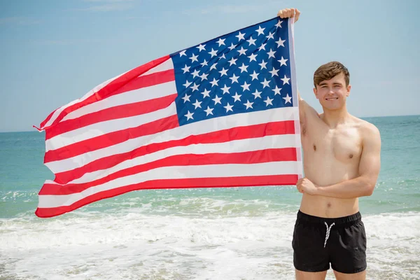 Blanke man op een strand met een Amerikaanse vlag — Stockfoto