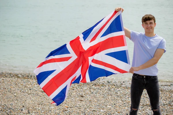 Blanc mâle sur une plage tenant un drapeau britannique — Photo