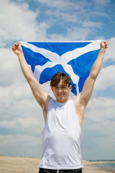 Kaukasischer Mann am Strand mit einer schottischen Flagge — Stockfoto