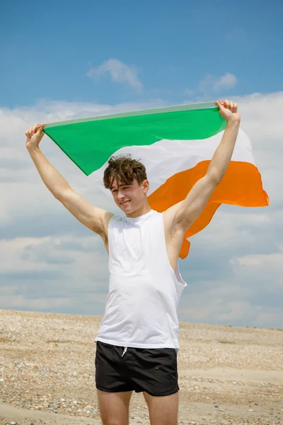 Kaukasischer Mann an einem Strand mit einer irischen Flagge — Stockfoto