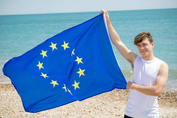 Beyaz erkek bir Avrupa Birliği bayrağı tutan bir plajda — Stok fotoğraf