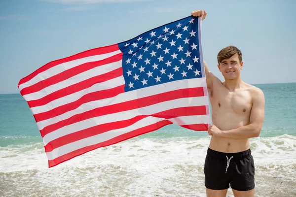 在沙滩上举着美国国旗的白种人男性 — 图库照片