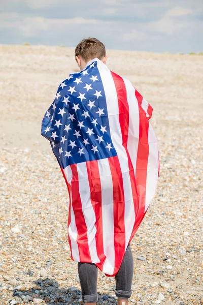 Caucasian male on a beach holding an American flag — Stock Photo, Image