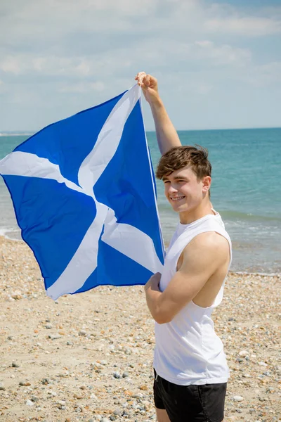 Blanc mâle sur une plage tenant un drapeau écossais — Photo