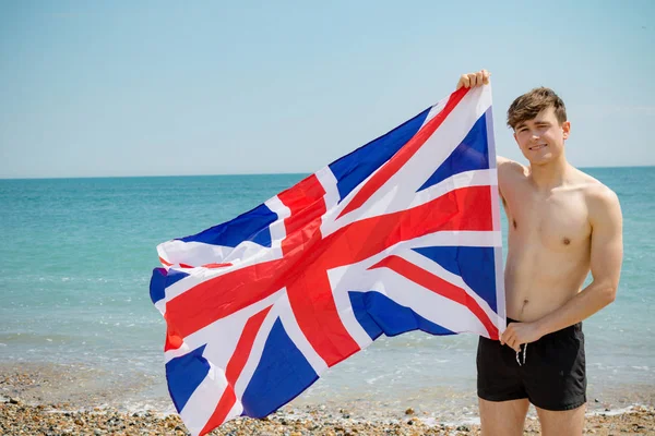 Blanc mâle sur une plage tenant un drapeau britannique — Photo